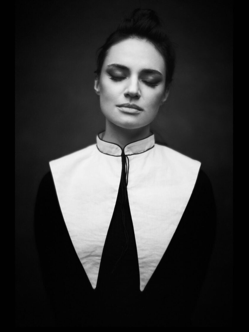 ein schwarz-weiss Portrait von einer Frau im dunklen Kleid mit weißem Kragen in gothic-chic