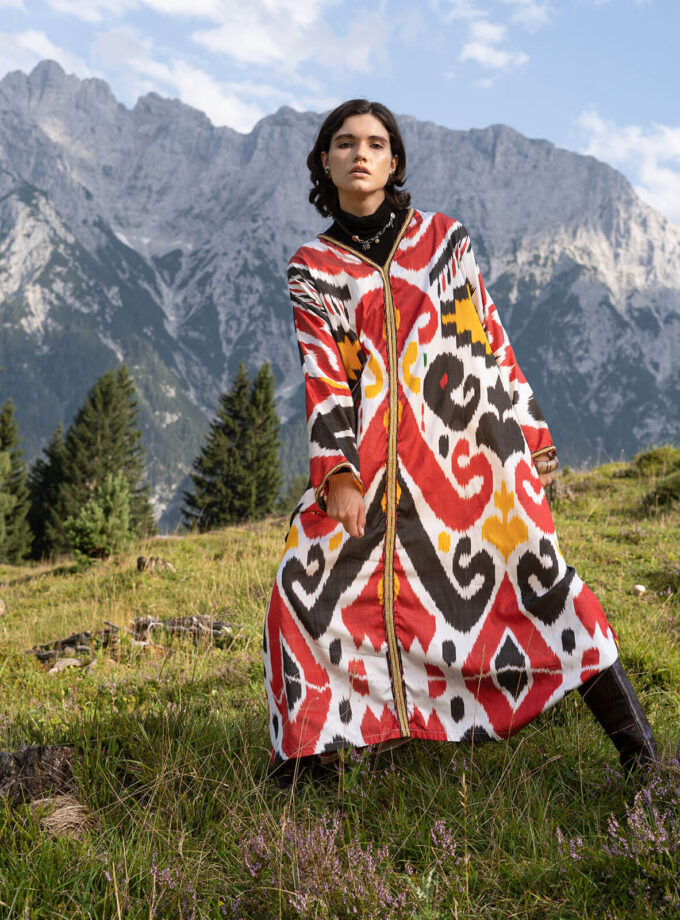 Berglandschaft mit junger Frau in einem buntem oversized Kaftan mit Ikat Mustern