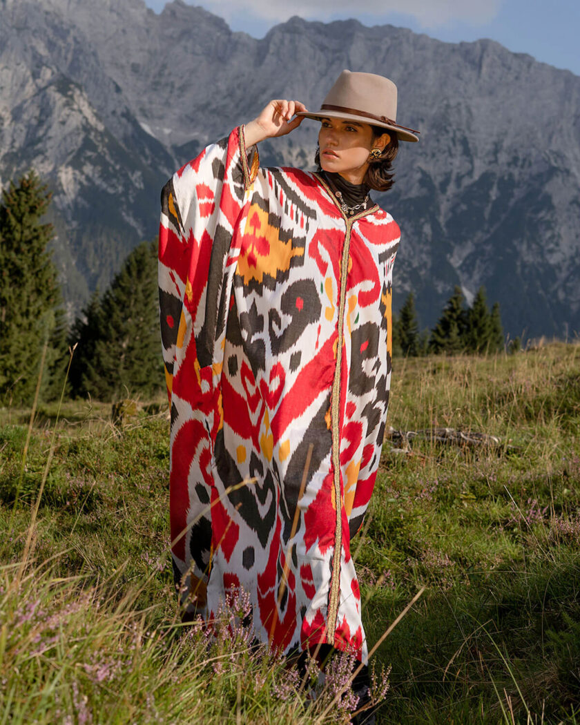 Berglandschaft mit junger Frau im Hut und einem buntem oversized Kaftan mit Ikat Mustern