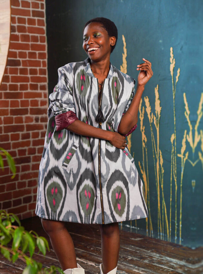 eine afroamerikanische Frau in einer weit geschnittenen knielangen Jacke mit bunten Prints