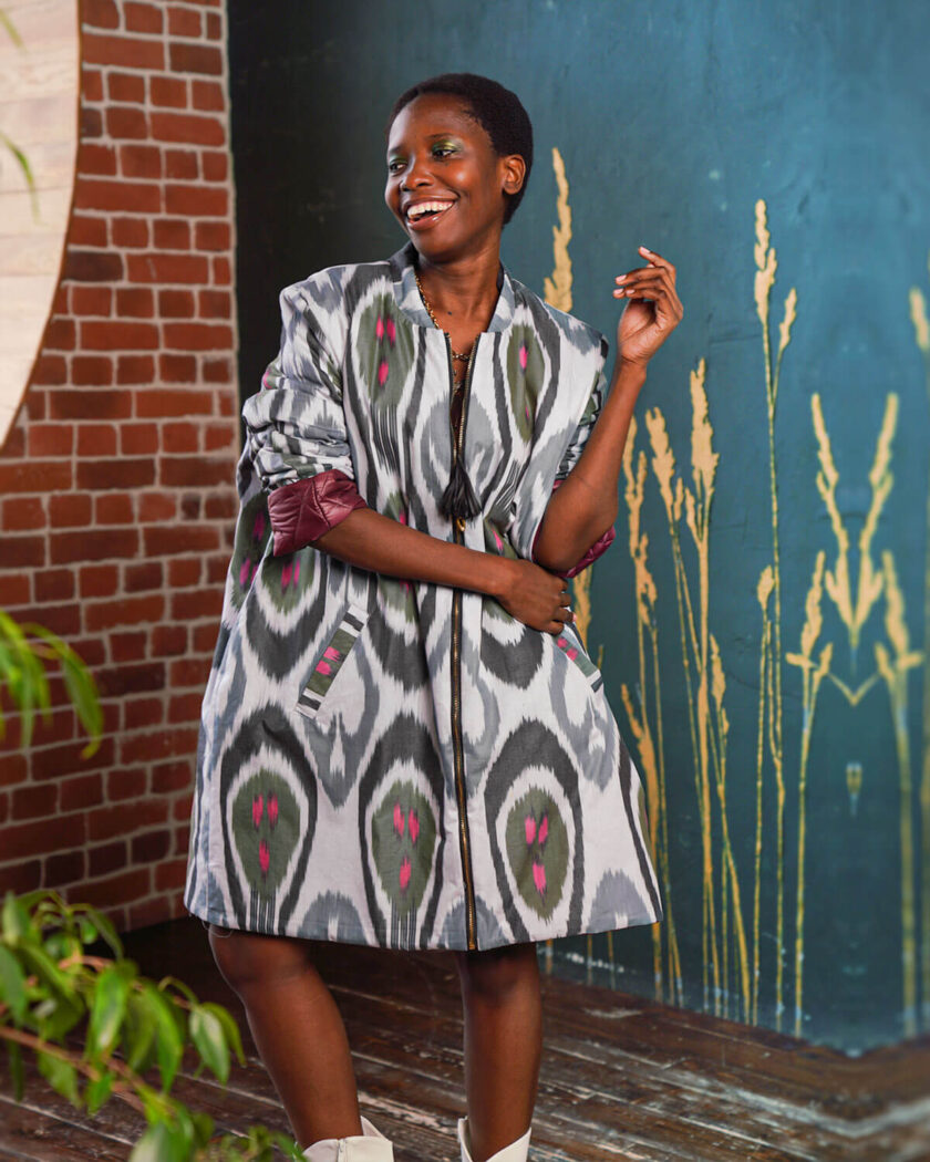 eine afroamerikanische Frau in einer weit geschnittenen knielangen Jacke mit bunten Prints
